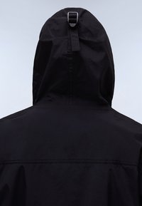 Giacca nera con cappuccio, dalla finitura liscia e opaca. Presenta una striscia regolabile sul retro del cappuccio e una vestibilità comoda. Senza motivi visibili.