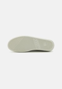Light gray rubber shoe sole with textured grip patterns and branding. Flat design with slight curves and no additional accents.