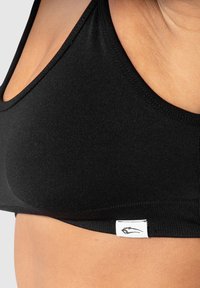 Zwarte sportbeha met een gladde textuur, driehoekig ontwerp, brede banden en een klein logo-label aan de zoom.