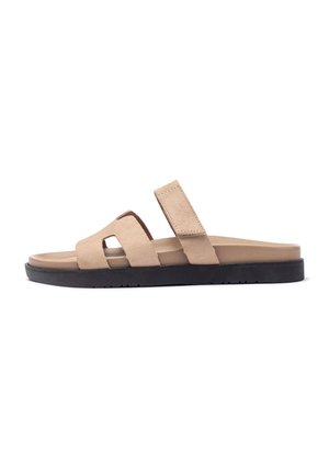 Beige suede slide sandals with a black rubber sole, featuring two wide straps and a cut-out design for ventilation and comfort.