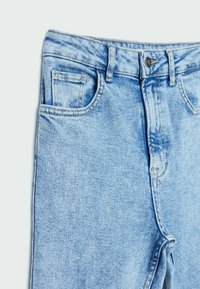 Jeans de mezclilla azul claro con una cintura alta, diseño de cinco bolsillos y detalles de costura visibles. La tela tiene una ligera textura y un acabado desvaído.