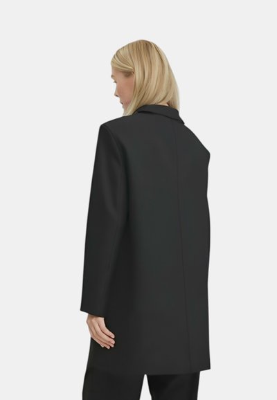 Cappotto nero con un design strutturato, dotato di collo a rever e una cucitura posteriore pulita. Realizzato in tessuto liscio e testurizzato, di lunghezza al ginocchio.