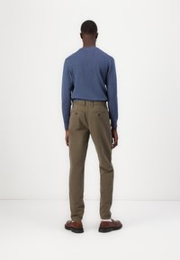 Blauer Pullover mit rundem Halsausschnitt, kombiniert mit olivgrünen Hosen. Das Outfit wird durch braune Schuhe ergänzt, die ein schlichtes, figuroptimiertes Design aufweisen.