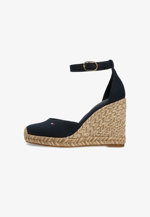 Marineblauwe sleehak espadrille met een opgevlochten jute plateauzool en enkelbandje met een gouden gesp.