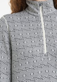 Felpa grigia con zip caratterizzata da un motivo a logo nero ripetuto, colletto alto e tessuto texturizzato con finitura liscia.