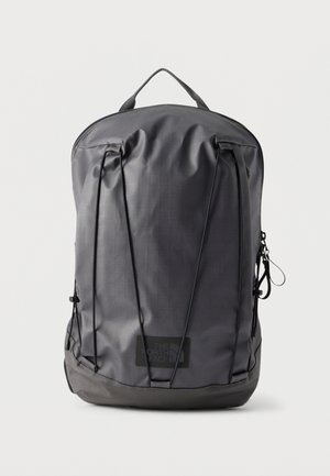 Black The North Face backpack with top handle, front elastic cords, and zippered pocket on a plain white background.