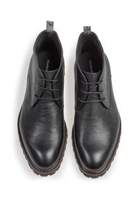 Zapatos de cuero negro con superficie texturizada, puntera redonda y diseño de cordones. Presenta una pequeña asa para tirar y una suela marrón duradera.