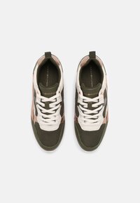Un par de zapatillas de Tommy Hilfiger en verde olivo, blanco y rosa, con cordones blancos, vistas desde arriba sobre un fondo gris claro.