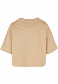 Kortermet, cropped t-skjorte i lys beige stoff. Har rund hals og avslappet passform med glatt, litt elastisk tekstur.