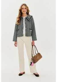 Šedá vzorovaná bunda s volánovým límcem, zlatými knoflíky a dvěma předními kapsami; spárována s krémovými kalhotami a hnědou kabelkou.