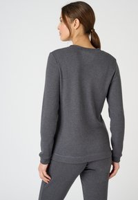 Grijze sweatshirt met lange mouwen, ribgebreide textuur en een ronde halslijn, gecombineerd met bijpassende grijze broek. Geen zichtbare patronen of hardware.