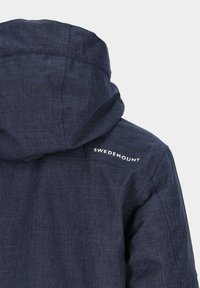 Marineblaue Kapuzenjacke aus strukturierter Stoff, mit einem Logo auf der linken Schulter. Das Design umfasst eine Kapuze und sichtbare Nähte.