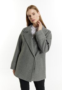 Grijze wolmix jas met een dubbelzijdig ontwerp, brede revers en een relaxte pasvorm. De mouwen zijn iets oversized en met een manchet.