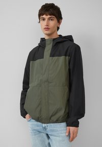 Lichte hoodiejack met een zwart bovenstuk en een olijfgroen onderstuk, voorzien van elastische manchetten en een ritsluiting.