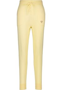 Gele gebreide joggingbroek met een koord in de taille, twee voorzakken en een kleine hartborduursel op de linkerzak.