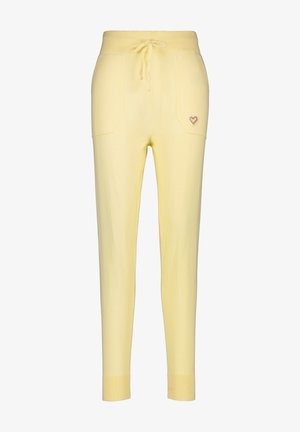 Gele gebreide joggingbroek met een koord in de taille, twee voorzakken en een kleine hartborduursel op de linkerzak.