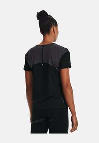 Svart atletisk t-shirt med en grå panel på baksidan, korta ärmar och rund halsringning; har en liten detalj och en åtsittande design.