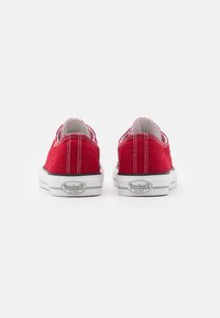 Scarpe slip-on in tela rossa con suole in gomma bianca, cuciture a contrasto e dettaglio del logo sul tallone. Design semplice con forma arrotondata.