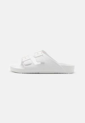 Sandalias deslizantes blancas con dos hebillas ajustables, una plantilla texturizada, una suela de goma flexible y un upper suave.
