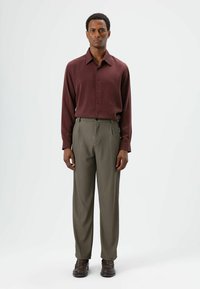 Maroon long-sleeve shirt with button closure paired with olive green pinstriped trousers. Brown shoes complete the outfit.