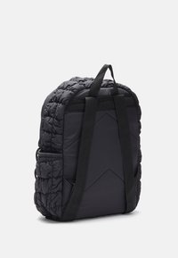 Mochila negra acolchada con tirantes acolchados, asa superior y bolsillo lateral elástico, vista desde atrás sobre un fondo blanco.