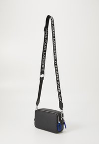 Black rectangular crossbody bag with textured material, zipper closure, adjustable strap featuring repeated logo, and blue accent detail.
