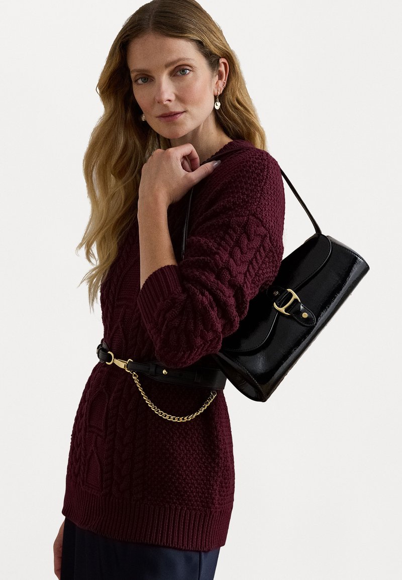 Burgundi árkötéses pulóver hosszú ujjakkal, fekete keresztpántos táskával párosítva, aranyszínű csattal és lánc részletekkel.