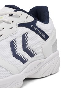 Vit sportskor med mesh-överdel, marinblå detaljer och randig logotyp. Har snörning, vadderad krage och texturerad sula för bra grepp.