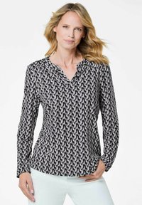 Blusa a maniche lunghe con motivo geometrico nero e grigio, caratterizzata da una scollatura a V e un tessuto morbido e leggero, con una leggera arricciatura sulle spalle.
