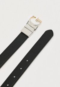 Μαύρη δερμάτινη ζώνη με ομαλή υφή, διαθέτει ασημένια μεταλλική αγκράφα και χρυσή λεπτομέρεια. Ρυθμιζόμενη με πολλαπλές τρύπες για το μέγεθος.