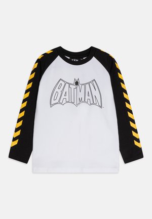 T-shirt z długim rękawem, biały korpus z czarnymi rękawami, żółty wzór chevron na rękawach, z grafiką "BATMAN" w czerni i szarości.