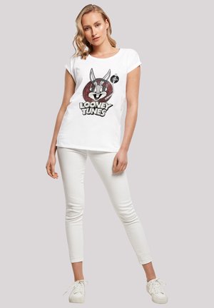 Hvit t-skjorte med kortermet som har et grafisk bilde av Bugs Bunny og teksten "Looney Tunes". Kombinert med hvite skinny jeans og hvite sneakers.