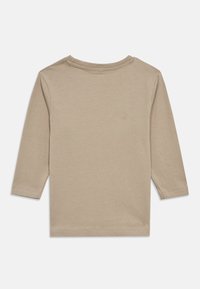 Μπεζ βαμβακερό πουκάμισο με μακριά μανίκια, στρογγυλή λαιμόκοψη και ίσιο τελείωμα. Διαθέτει απλές ραφές και δεν έχει ορατά σχέδια ή διακοσμητικά στοιχεία.