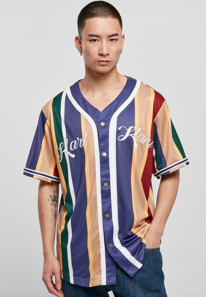 Flerfarget baseballstils skjorte med vertikale striper i gult, blått, grønt og rødt, med knappfront og brodert skrift.