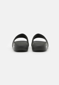 Chinelos pretos de flip-flop com parte de trás aberta, material sintético liso, sola plana e detalhes texturizados subtis nas tiras.