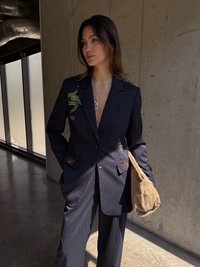 Jūrinio stiliaus juostuotai švarkas su žalia gyvatės siuvinėjimu ir daugiakampėmis kišenėmis, derinamas su smėlio spalvos važiuoklės krepšiu.