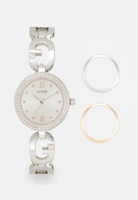 Orologio in metallo argentato con cassa rotonda, bezzi in cristallo, dettagli in oro rosa e due bezzi intercambiabili: argento e oro rosa.