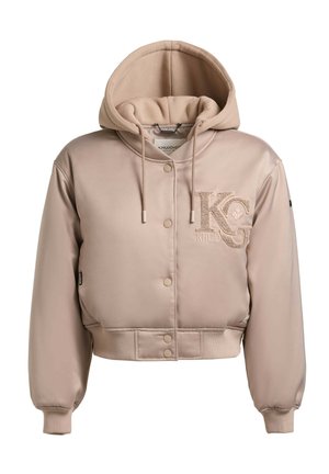 Bézs színű, rövidített dzseki bélelt testtel, húzózsinórokkal ellátott csuklyával, elől patentos gombokkal, bordás mandzsettákkal és szegéllyel, valamint a mellkason „KG KHUJO” logóval.