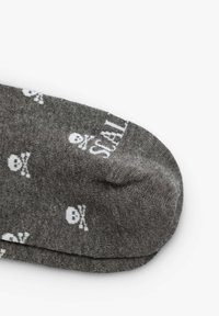 Calzini alla caviglia grigi con motivo di teschi bianchi. Texture liscia con punta e tallone rinforzati. Presenta il nome del marchio "SCALP" stampato vicino alla cima.