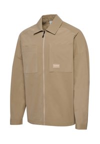 Beżowa kurtka na zamek z dwoma dużymi kieszeniami na piersi, jedna z małą naszywką z logo "hummel" oraz klasycznym kołnierzem.
