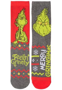 Calze grigie e rosse con il Grinch. Una calza presenta il testo "Sentirsi Grinchoso"; l'altra dice "Buon Grinchmas" con motivi festivi.