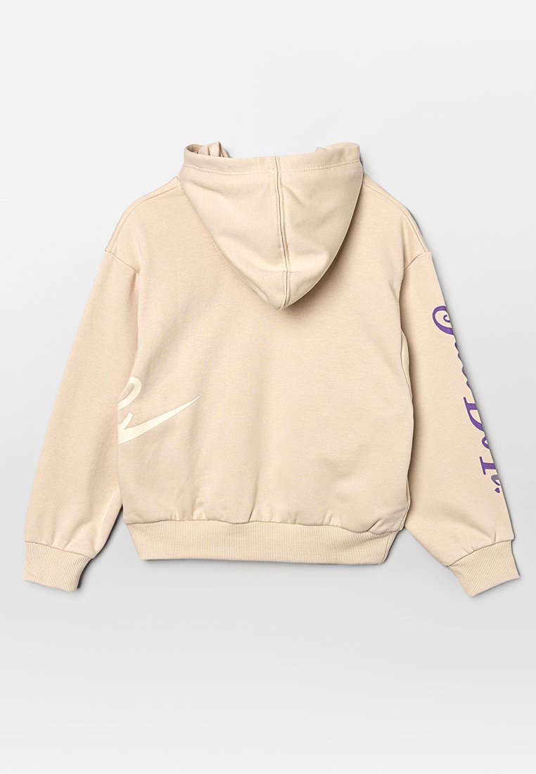 Haut à capuche beige avec une capuche, tissu texturé, ourlet et poignets côtelés. Présente un logo Nike blanc et un texte violet sur la manche gauche.