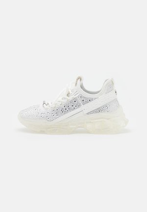 Biały sneaker z przezroczystą grubą podeszwą, ozdobiony srebrnymi cyrkoniami i białymi sznurowadłami, z boku oznaczony tłoczonym brandingiem.