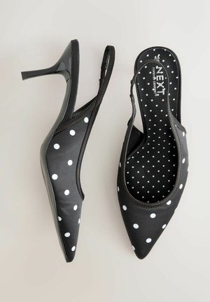 Décolleté slingback nere con pois bianchi, punta appuntita, finitura lucida e tacco a stiletto sottile. Tomaia in tessuto morbido e soletta imbottita.