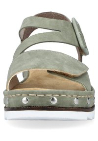 Sandale en suede vert avec des brides croisées, boucle ajustable et accents cloutés sur la semelle. Semelle intérieure texturée et semelle extérieure en caoutchouc blanc.