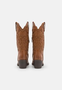 Stivali da cowboy in pelle marrone con punta appuntita, motivi ricamati a spirale e maniglie per una facile calzata. Il tacco di altezza media completa il design.