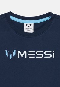 Tamno plava pamučna majica s okruglim ovratnikom, koja na sebi ima svijetloplavi logo i tekst "MESSI" u bijeloj boji. Mekana tekstura i jednostavan dizajn.