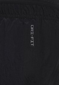 Čierne DRI-FIT šortky, vyrobené z ľahkého nylonového materiálu s textúrovaným povrchom, s elastickým pásom a šitými švami.