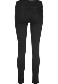 Vaqueros ajustados negros de denim con una textura suave. Presentan bolsillos traseros y un diseño de corte slim que se estrecha desde la cintura hasta el tobillo.