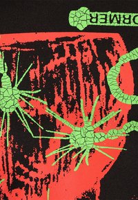 Black fabric featuring a cracked texture. Bright red and green graphic design with abstract shapes resembling spikes and organic forms.